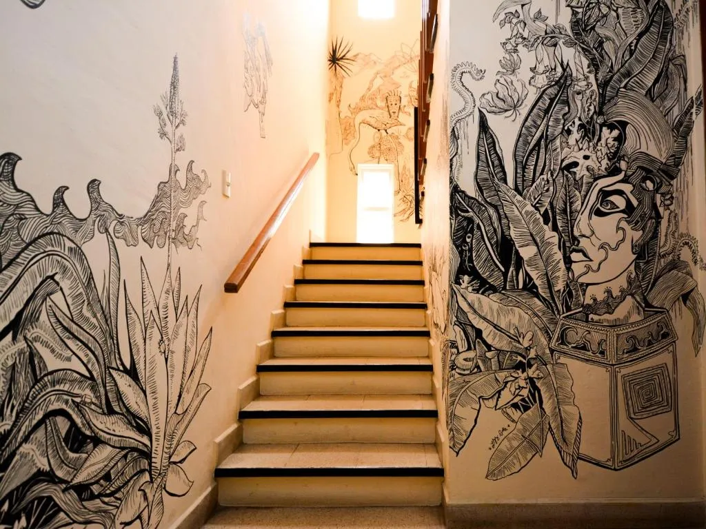 Stairway with ink murals of plants and Oaxacan faces